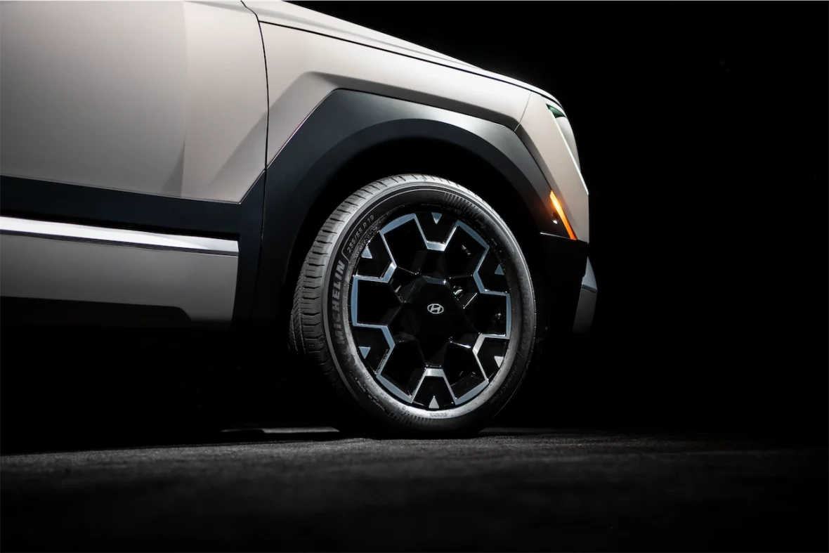 Close-up of a vehicle's wheel and fender in a low-light setting, featuring a modern alloy wheel design.