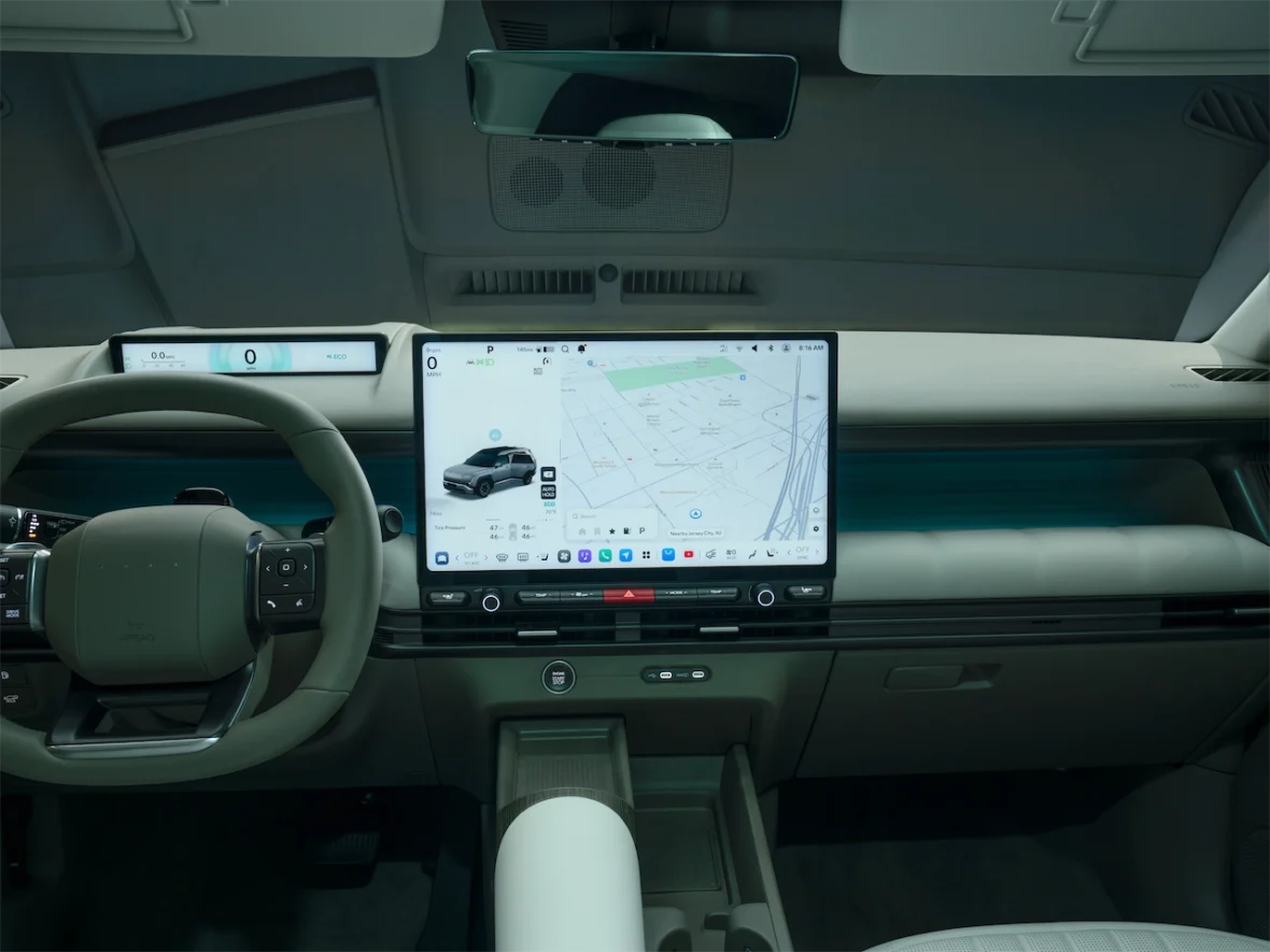 Interior of a modern electric vehicle featuring a large touchscreen display, a digital dashboard, and a minimalist steering wheel.