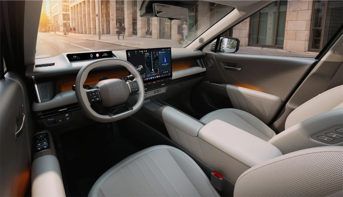 Interior view of a modern car showcasing a sleek dashboard with advanced technology display, a minimalist steering wheel, and stylish seating in a bright environment.