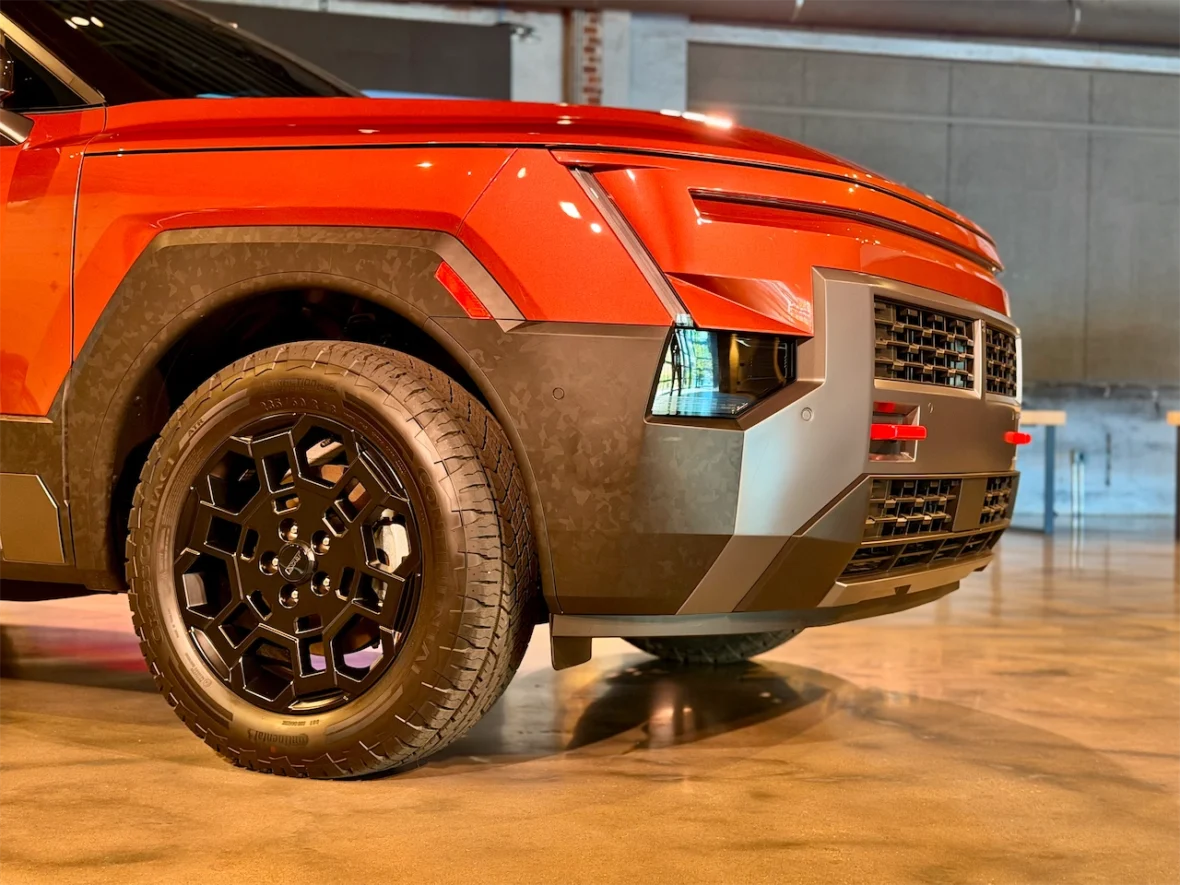 Close-up view of a shiny orange vehicle showcasing its bold front design and black alloy wheel.