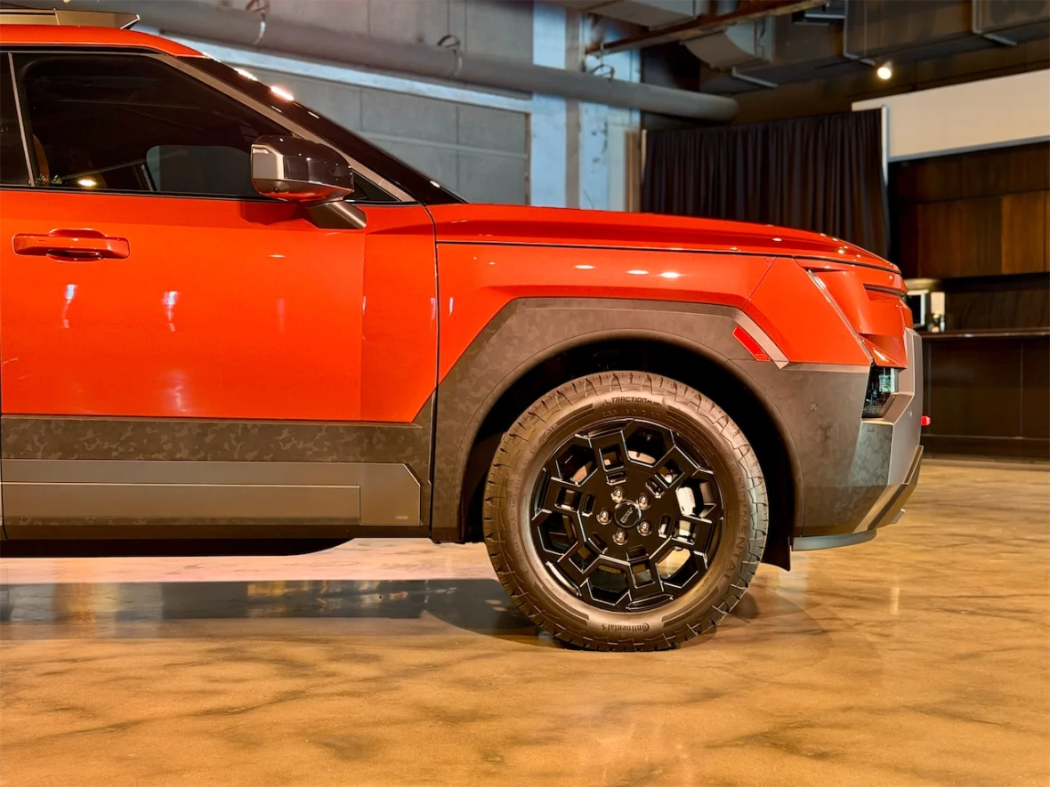 Close-up view of the side of a red SUV showcasing its black alloy wheel and modern design elements.