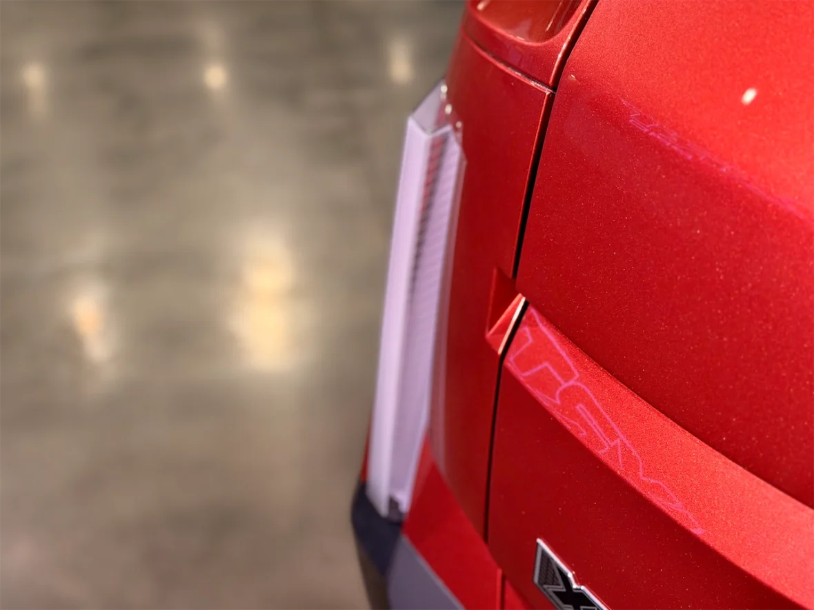 Close-up view of the rear of a red vehicle, showcasing the tail light and emblem.