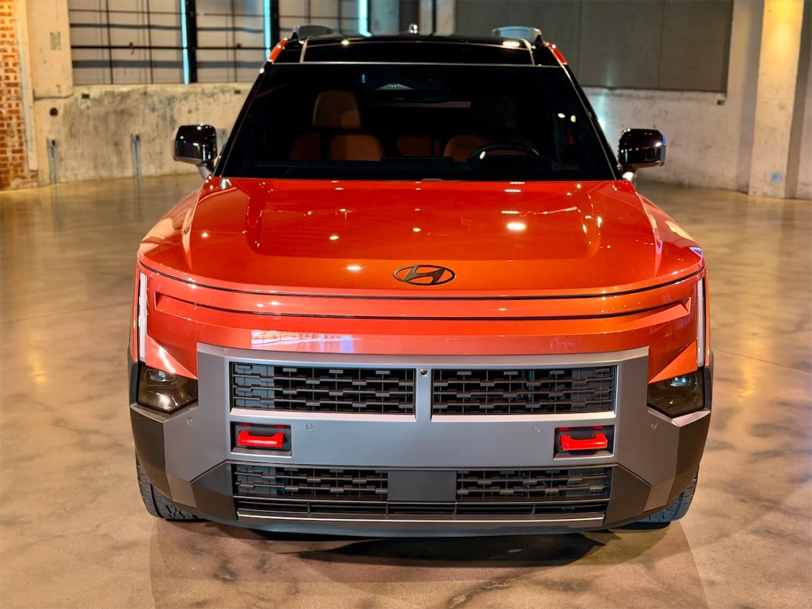 Front view of an orange Hyundai vehicle showcasing a modern design with a distinctive grille and sleek lines.