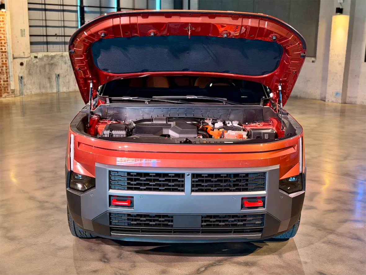 Front view of a car with the hood open, showcasing the engine compartment in a modern indoor setting.