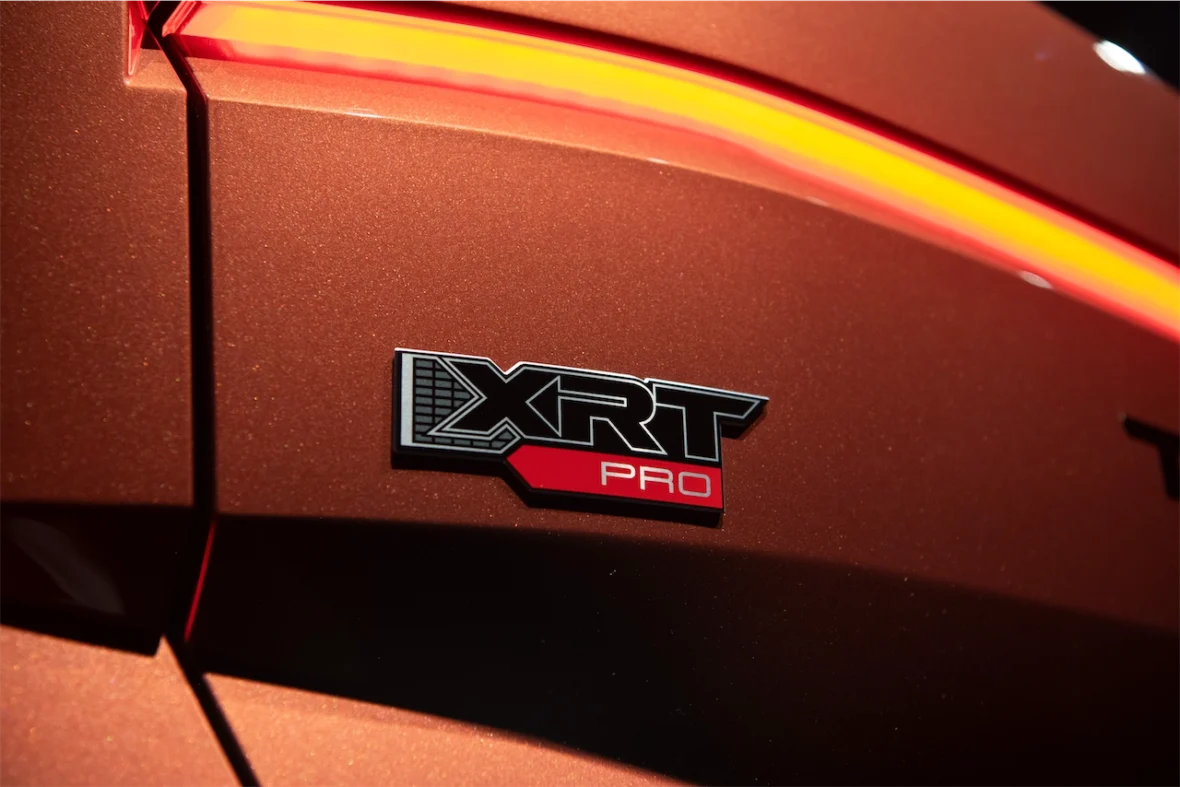 Close-up of the 'XRT PRO' badge on a car's rear, set against a sparkling orange surface.
