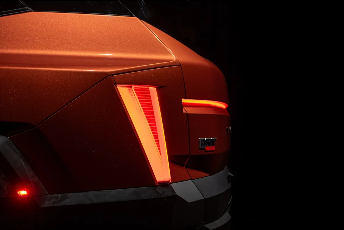 Close-up of the rear corner of a modern vehicle showcasing its orange paint and distinctive tail light design.