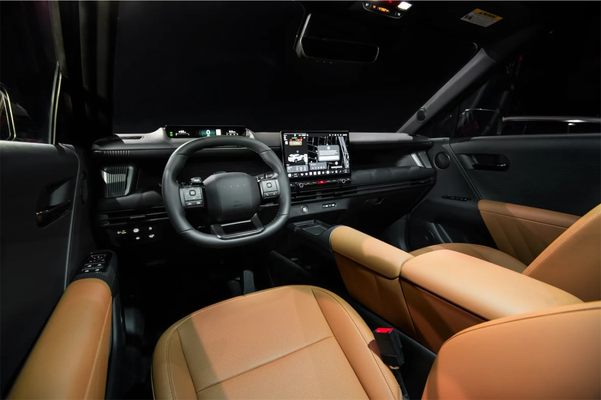Interior view of a modern car featuring a leather steering wheel, a dashboard with digital displays, and tan leather seats.
