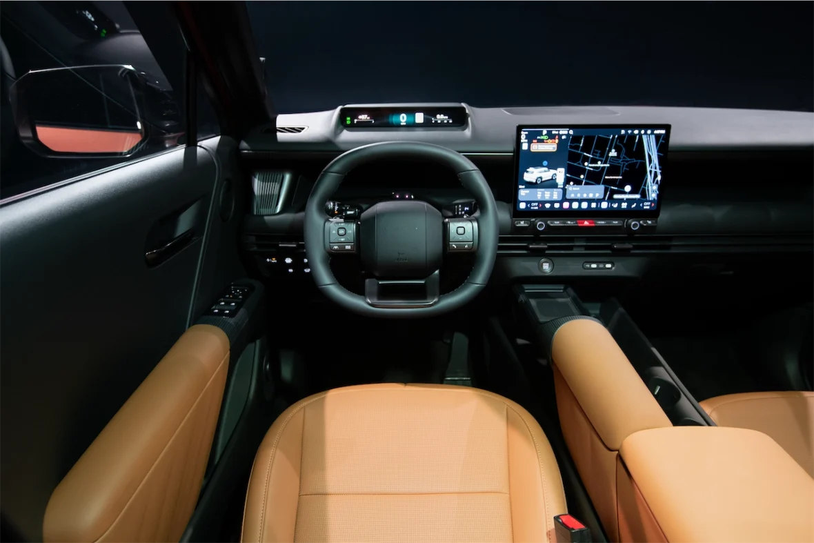 Interior view of a modern car dashboard with a steering wheel, digital display, and leather seats.