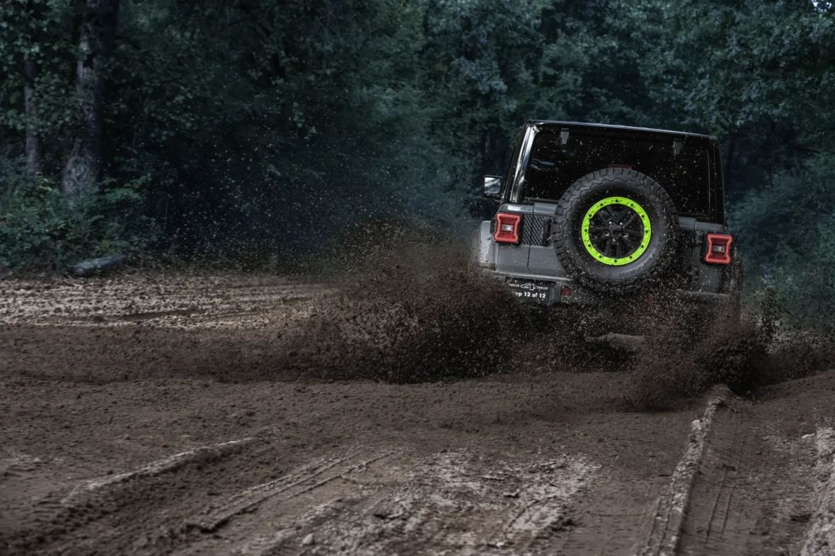 Rear view of a Jeep Wrangler Switchback driving through mud