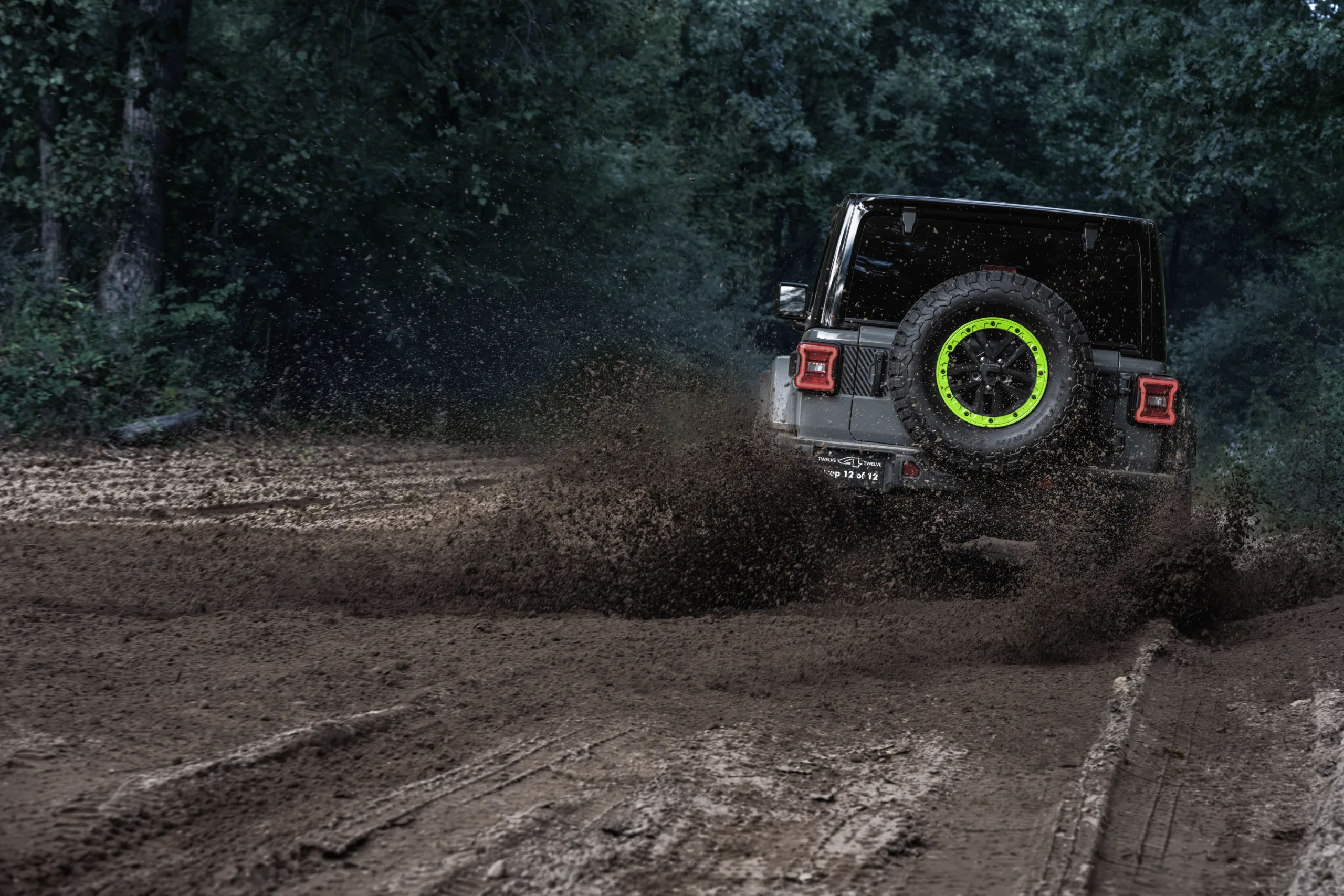 Rear view of a Jeep Wrangler Switchback driving through mud