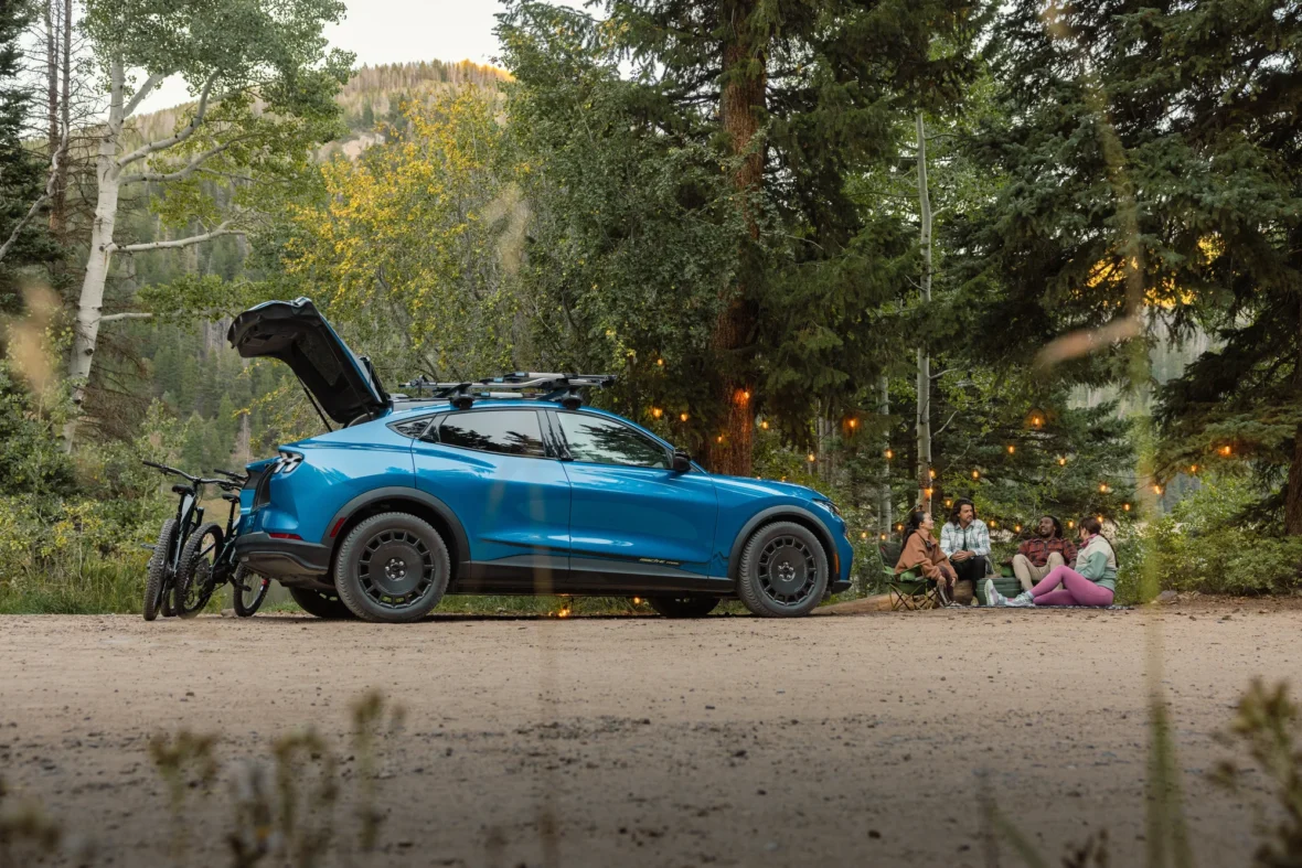 Friends relaxing at a campsite next to a 2027 Mustang Mach-E Trail
