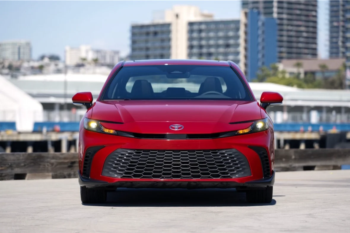 Front view of a red car with a distinctive grille and sleek design, parked in an urban setting with buildings in the background.