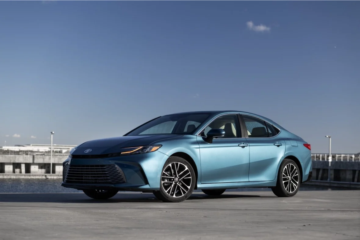 A blue Toyota sedan parked on a concrete surface with a clear blue sky in the background.