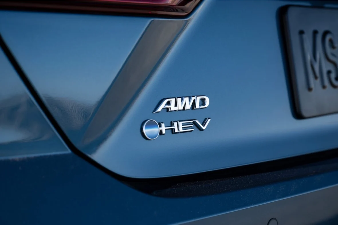 Close-up of a vehicle's rear showing AWD and HEV badges on a blue surface.