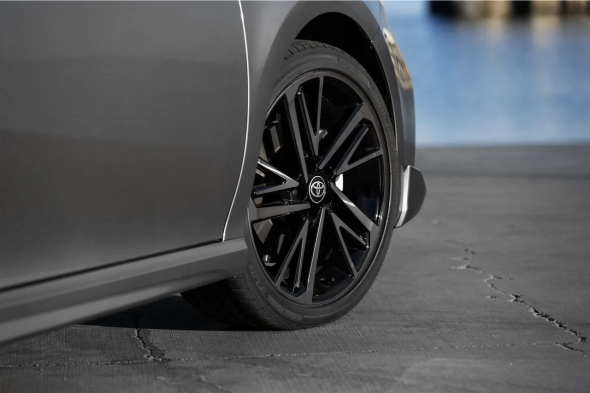 Close-up of a black alloy wheel on a gray car, showcasing the tire and part of the vehicle's body.