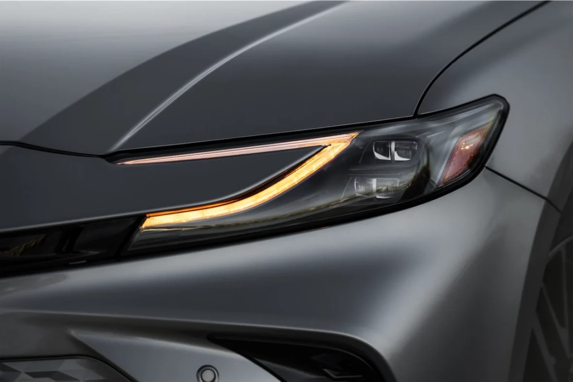 Close-up of a modern car headlight and front grille with sleek design elements.