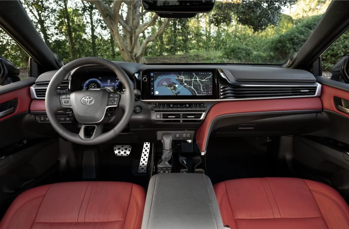 Interior view of a modern car featuring a steering wheel, digital dashboard display, and a central touchscreen with navigation.