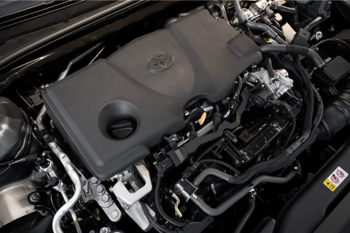 Close-up view of a Toyota engine, showcasing the engine cover, various pipes, and components underneath the hood.
