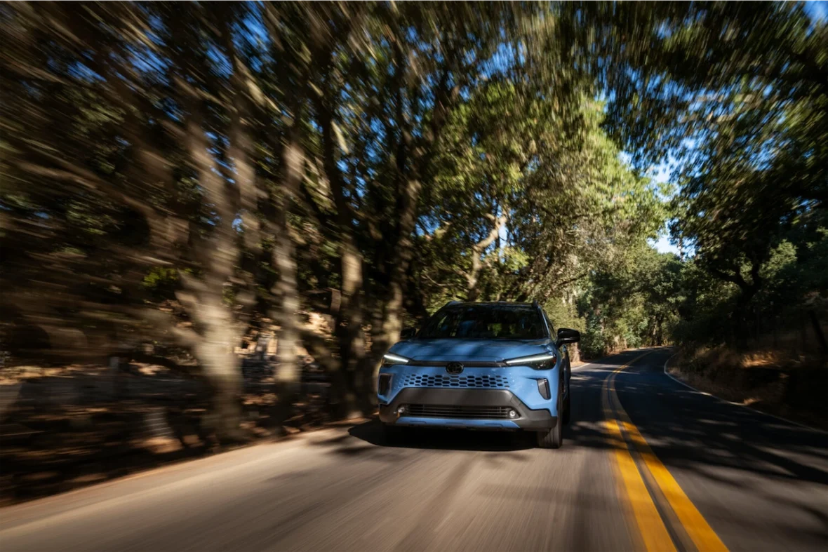 2027 Toyota Corolla Cross Hybrid XSE driving on a tree-lined road