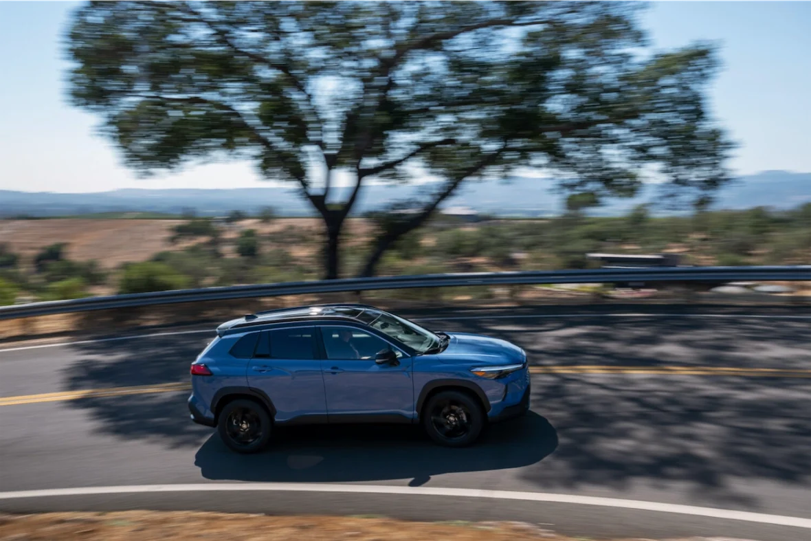 Side view of the Corolla Cross Hybrid XSE driving on a country road