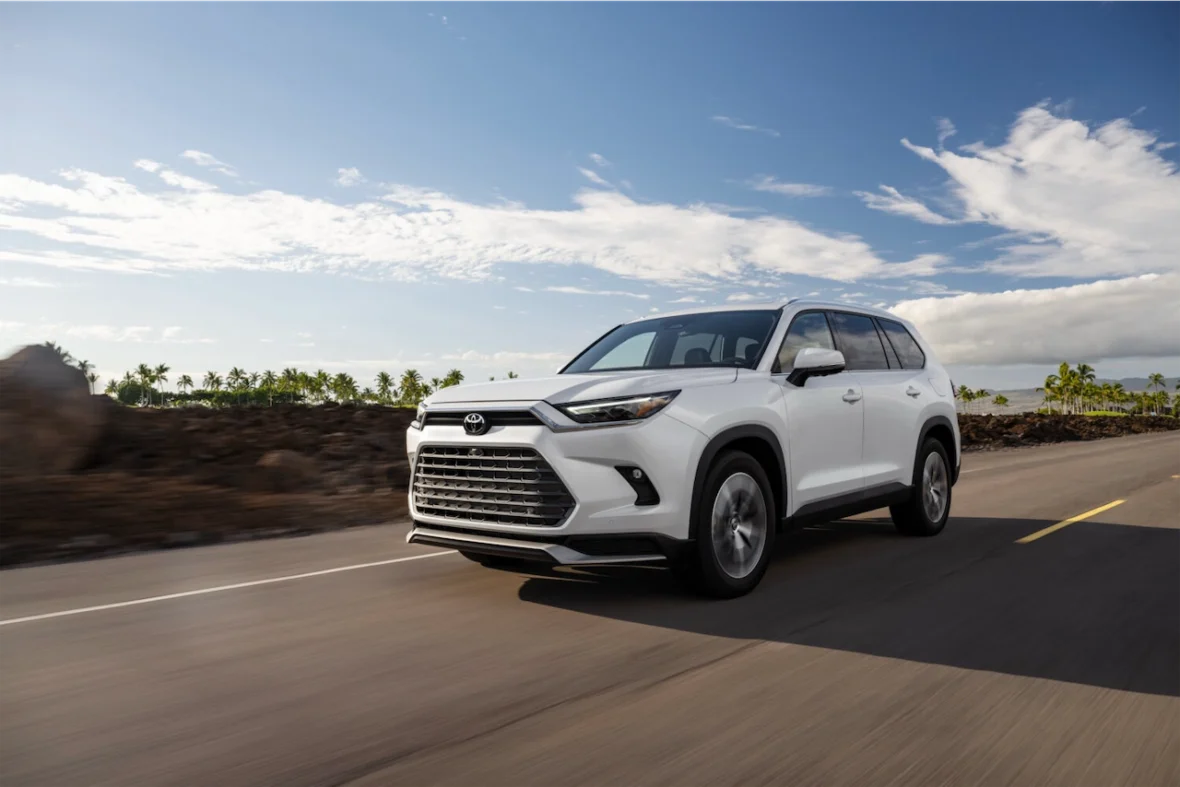 2027 Toyota Grand Highlander Limited in Wind Chill Pearl driving on an open road lined with palm trees