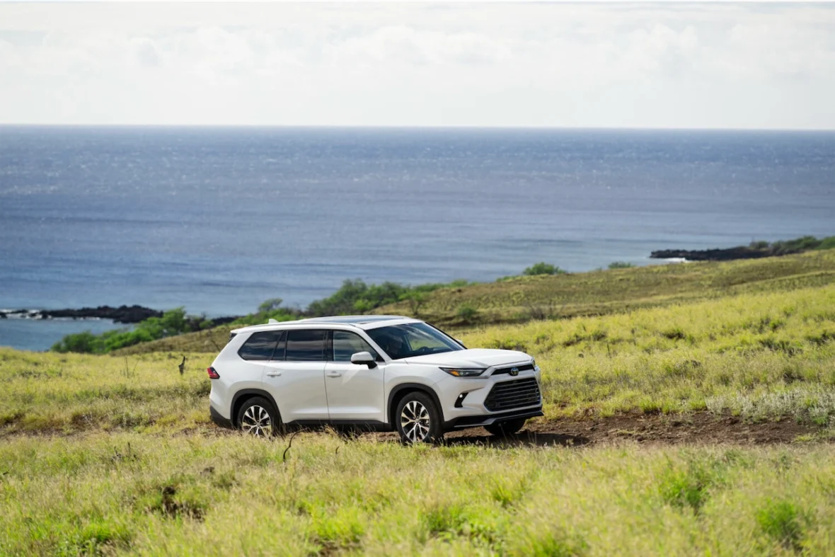 Toyota's three-row SUV parked on a grassy hillside overlooking the ocean