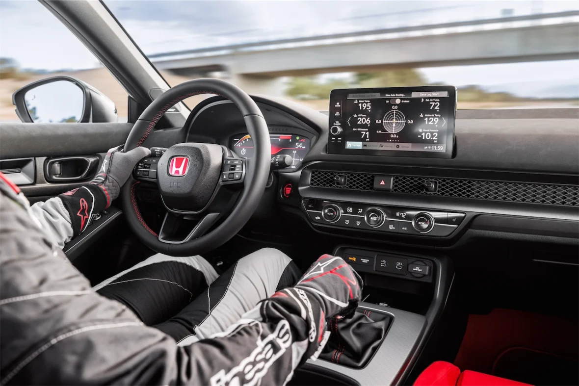 Driver in racing gloves at the wheel of a 2027 Honda Civic Type R with the digital gauges lit
