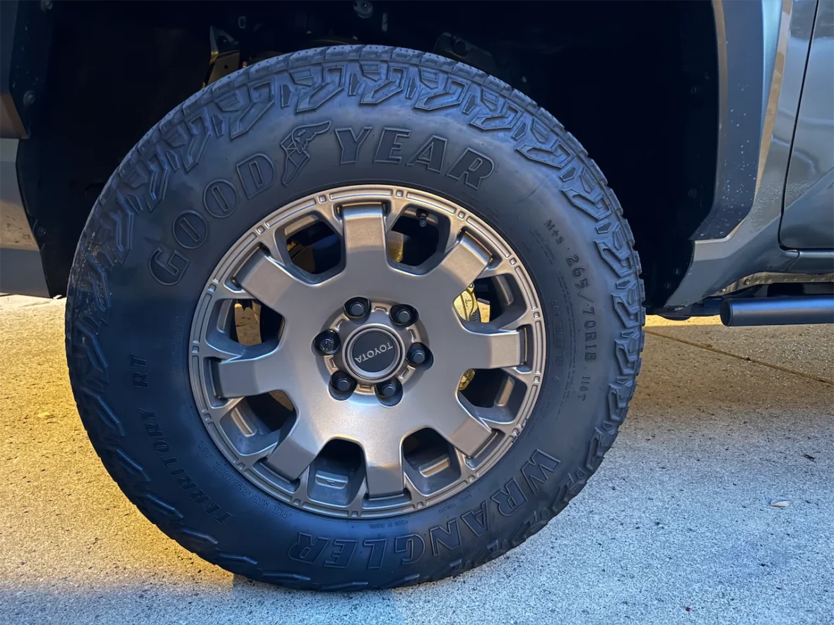 Close-up of a silver alloy wheel with a black off-road tire, featuring the GoodYear and Wrangler RT branding.