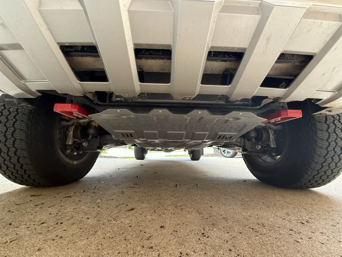 View of the underside of a vehicle showcasing the suspension, wheel, and protective skid plate.