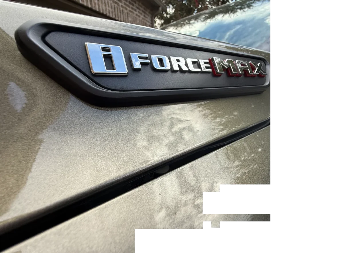 Close-up of a vehicle emblem featuring the text 'i FORCE MAX' on a metallic surface.