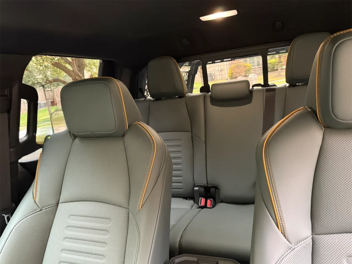 Interior view of a vehicle showing grey leather seats with orange stitching and ample space.