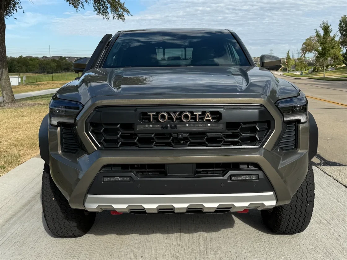 Front view of the 2026 Toyota Tacoma Trailhunter in Bronze Oxide parked on a concrete driveway.