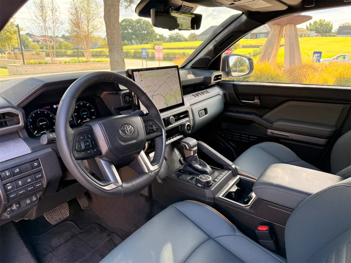 Interior view of a Toyota vehicle showcasing the steering wheel, dashboard with navigation screen, and front seats.