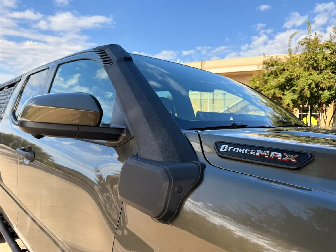 Close-up of a gray vehicle showcasing a side mirror and the 'iForce Max' badge on the front fender under a blue sky.