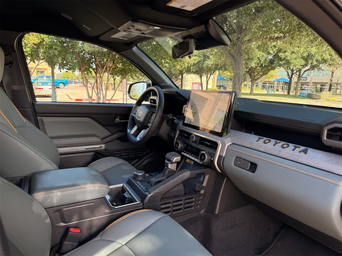 Interior view of a modern Toyota vehicle showcasing the dashboard, steering wheel, and seats, with a large touchscreen display and distinctive design elements.