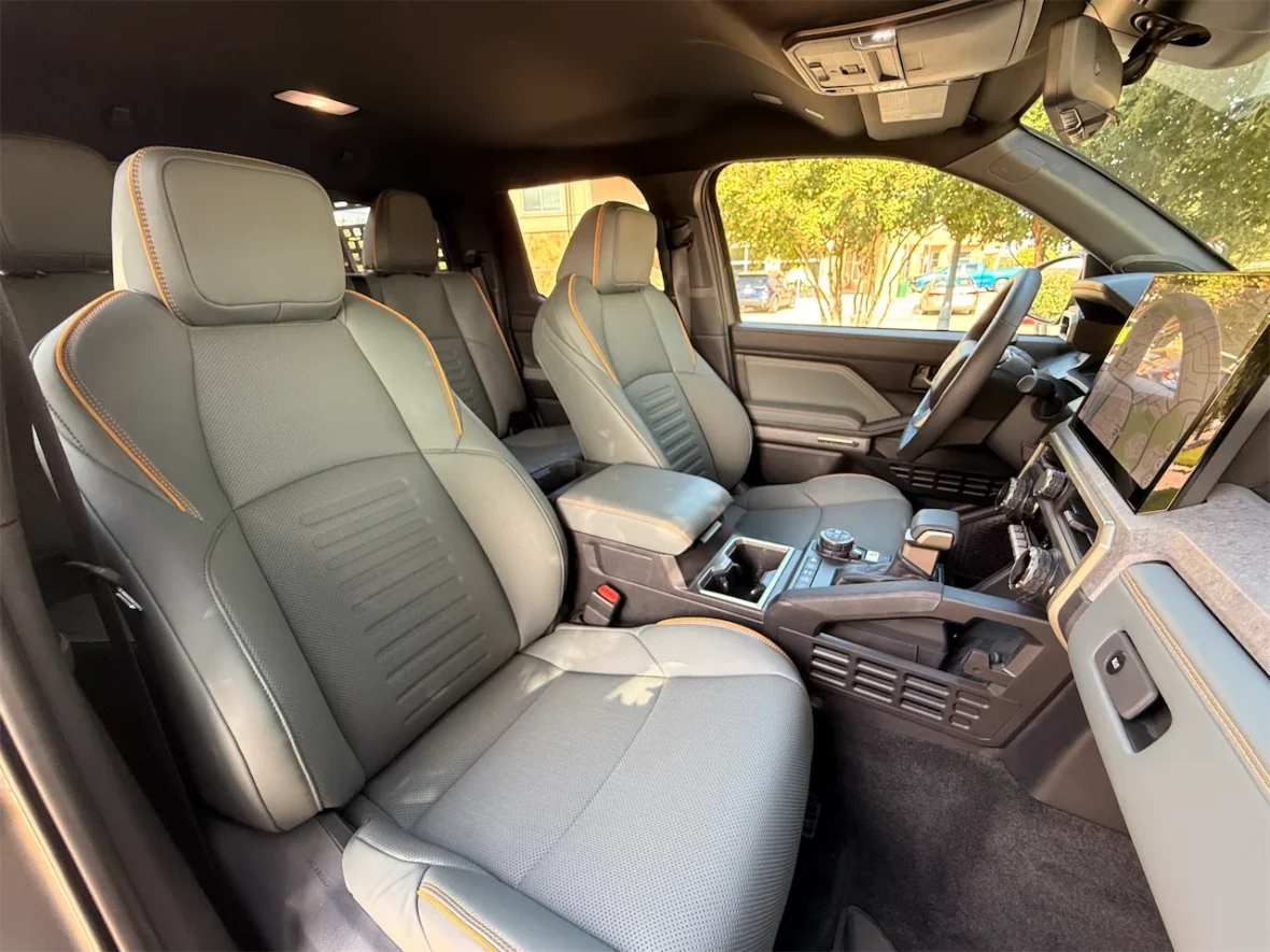 Interior view of a modern vehicle showing two front seats, center console, and dashboard with large touchscreen display.