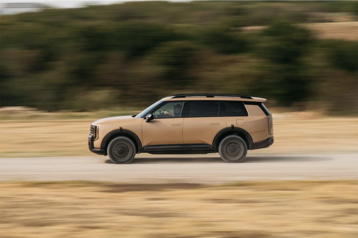 A tan SUV driving on a gravel road, with motion blur suggesting high speed.