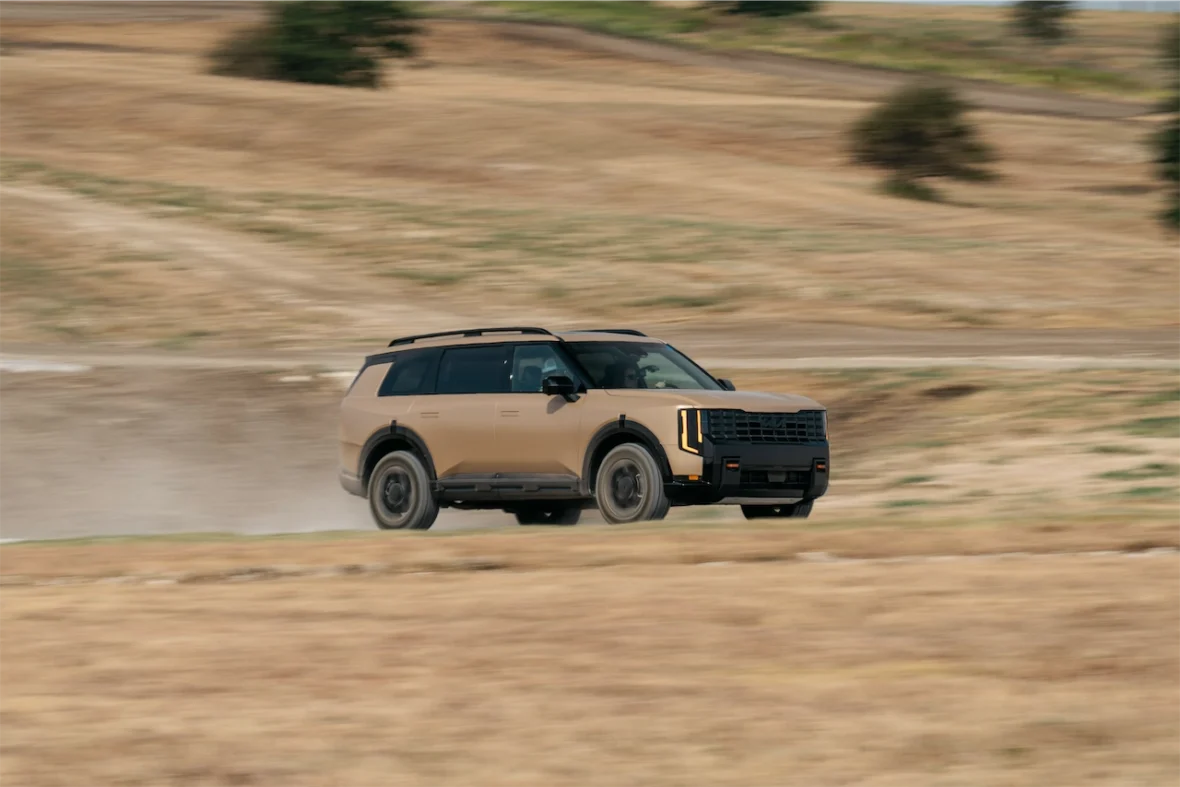 A tan SUV driving on a dirt road, kicking up dust with a blurred background, showcasing its off-road capabilities.