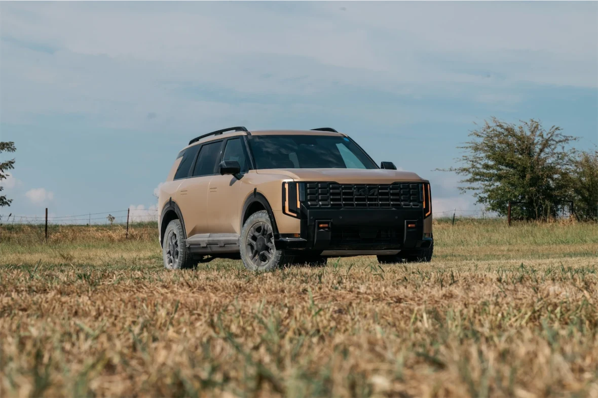 A rugged SUV parked on a grassy field with a clear blue sky in the background.