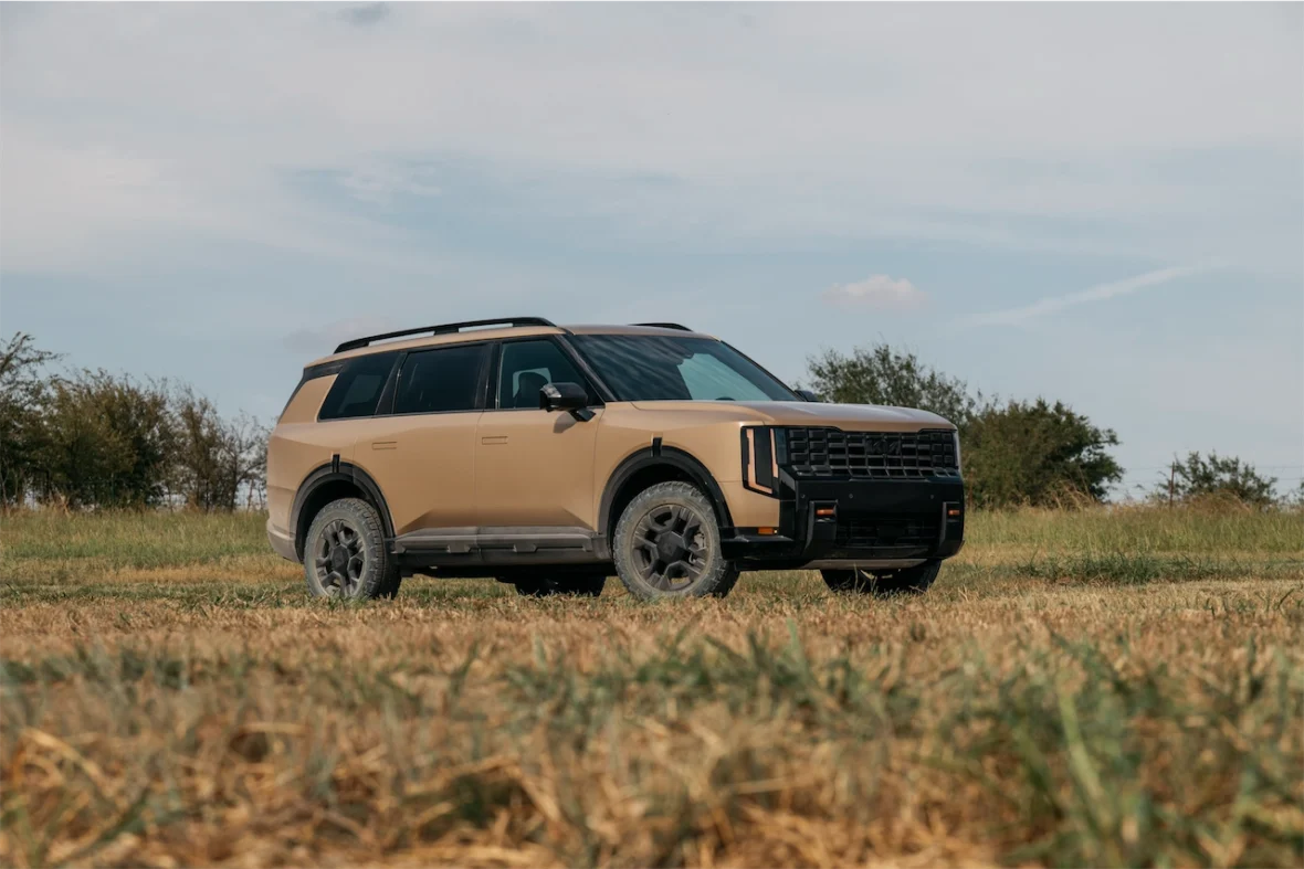 A modern SUV parked on an open field with dry grass, featuring a two-tone color scheme and rugged tires.