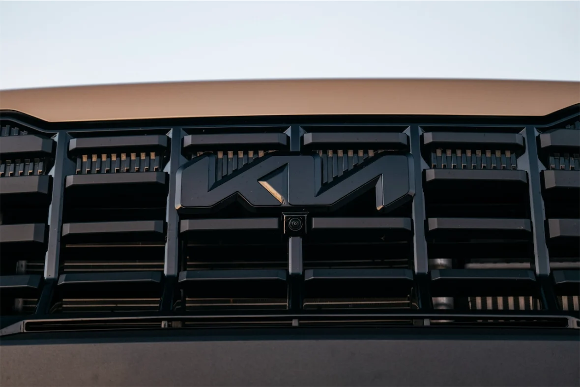 Close-up of a black Kia logo on a vehicle's front grille.