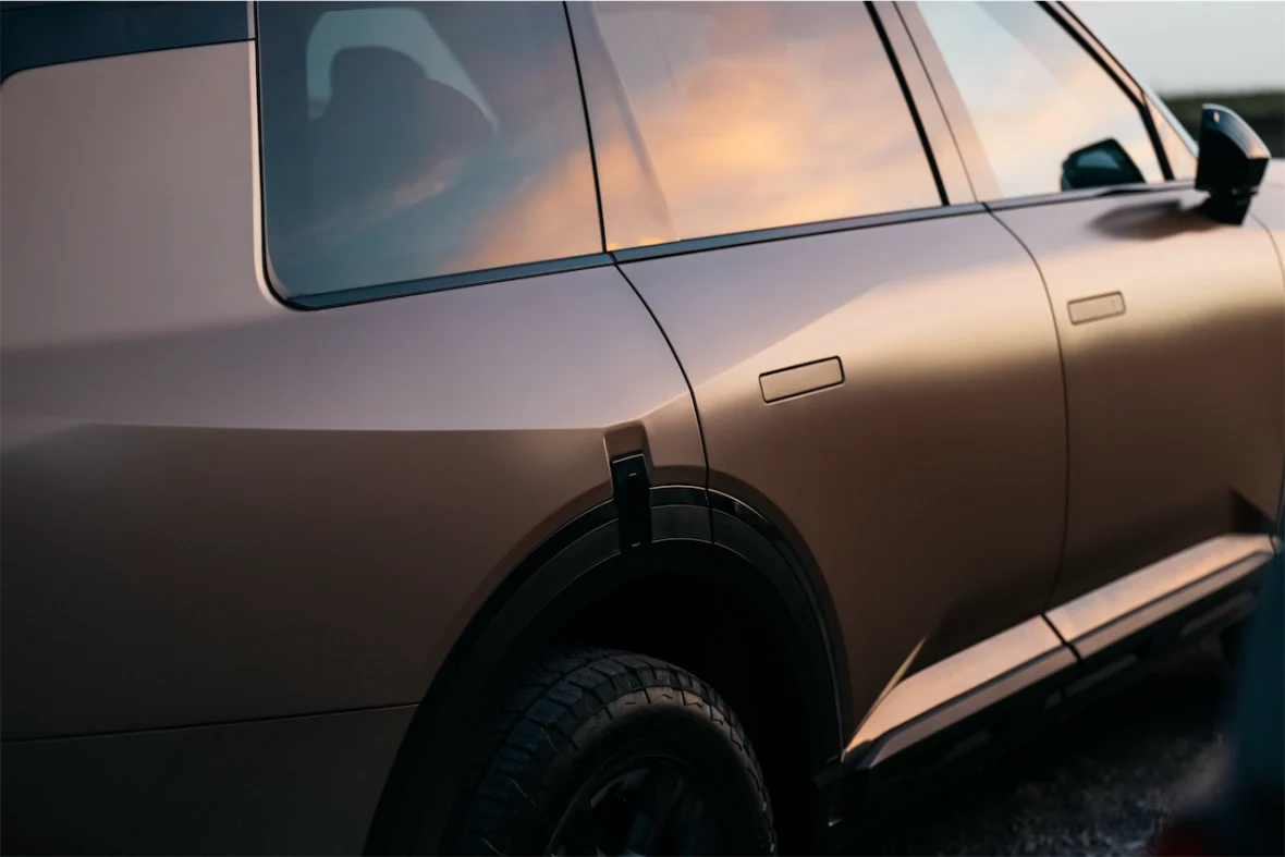 Close-up of the rear side of a modern, matte-finished vehicle, highlighting the sleek design and reflection of the sky on the surface.