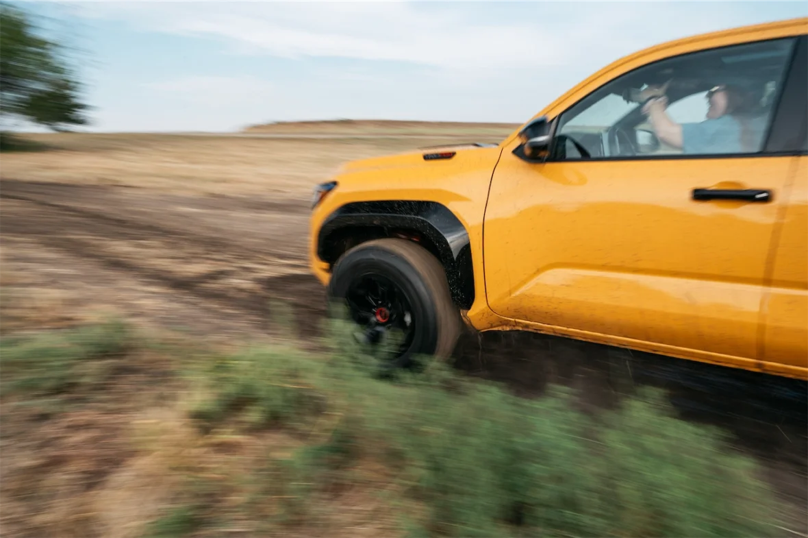 A yellow off-road vehicle navigating a dirt path, with motion blur indicating speed.