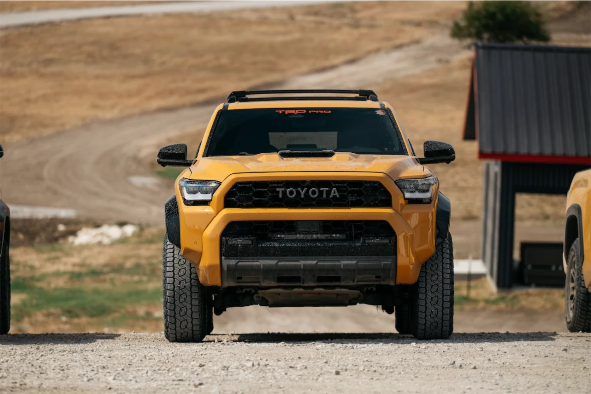 Front view of a yellow Toyota truck parked on a gravel driveway, showcasing its rugged design and off-road capabilities.
