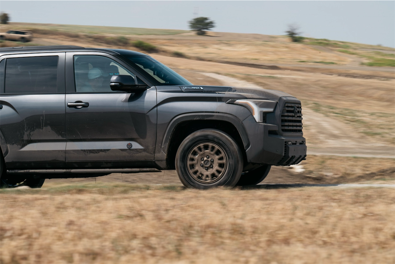 Profile of a gray 2027 Toyota Sequoia Trailhunter with bronze wheels on a dirt trail